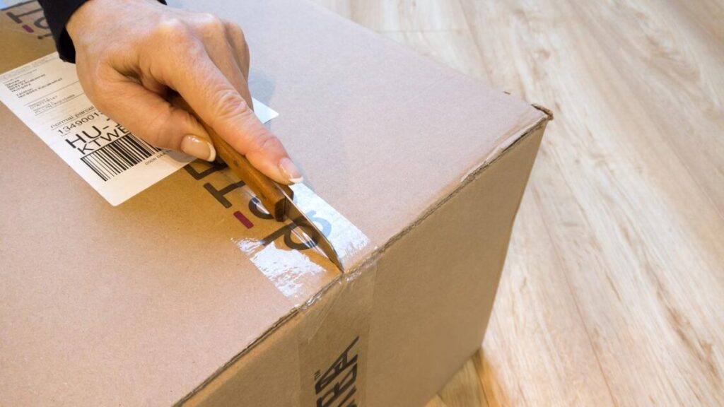 Man bedient verhuislift zelf en verplaatst kartonnen dozen naar boven in een gebouw met meerdere verdiepingen