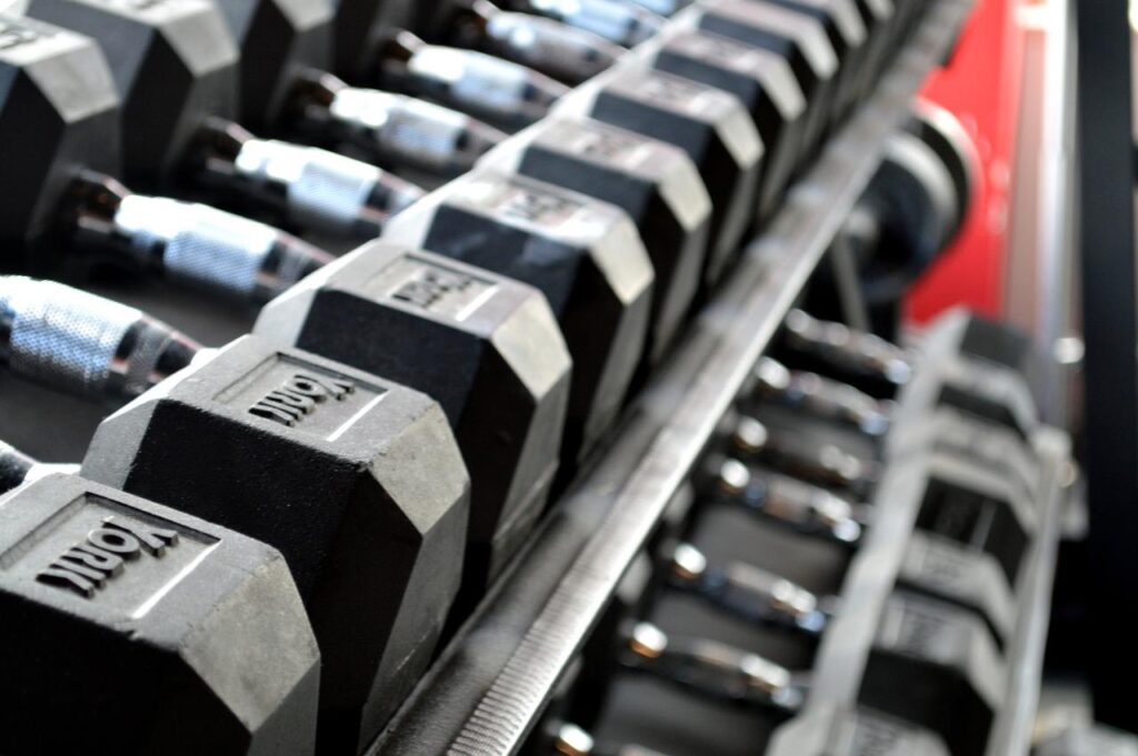 Persoon voert een routine op in de sportschool met halters en diverse trainingsapparatuur